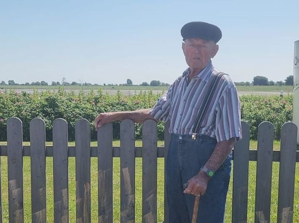 Älterer Herr vor Gartenzaun im Garten