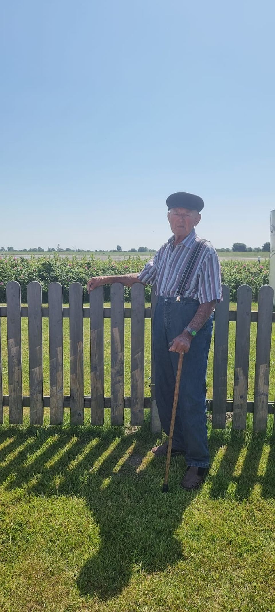 Älterer Herr vor Gartenzaun im Garten