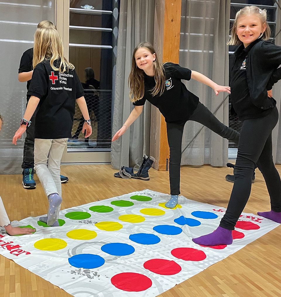 Kinder vom JRK gestalten ein Plakat und spielen auf den roten Punkten