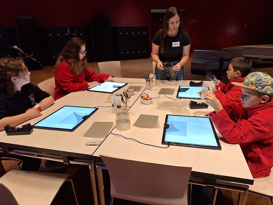 Kinder beim Besuch der Experimenta, sitzend am Tisch mit Tablets
