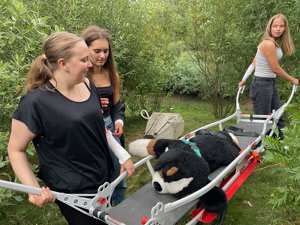 Jugendliche trainieren für die Bergwacht. Ein Stoffhund wird auf der Bahre getragen.