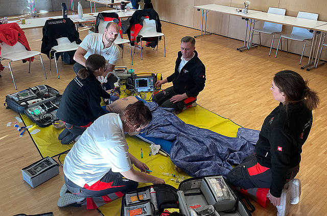 Teilnehmer sitzen bei einer Erste Hilfe Übung auf den Boden