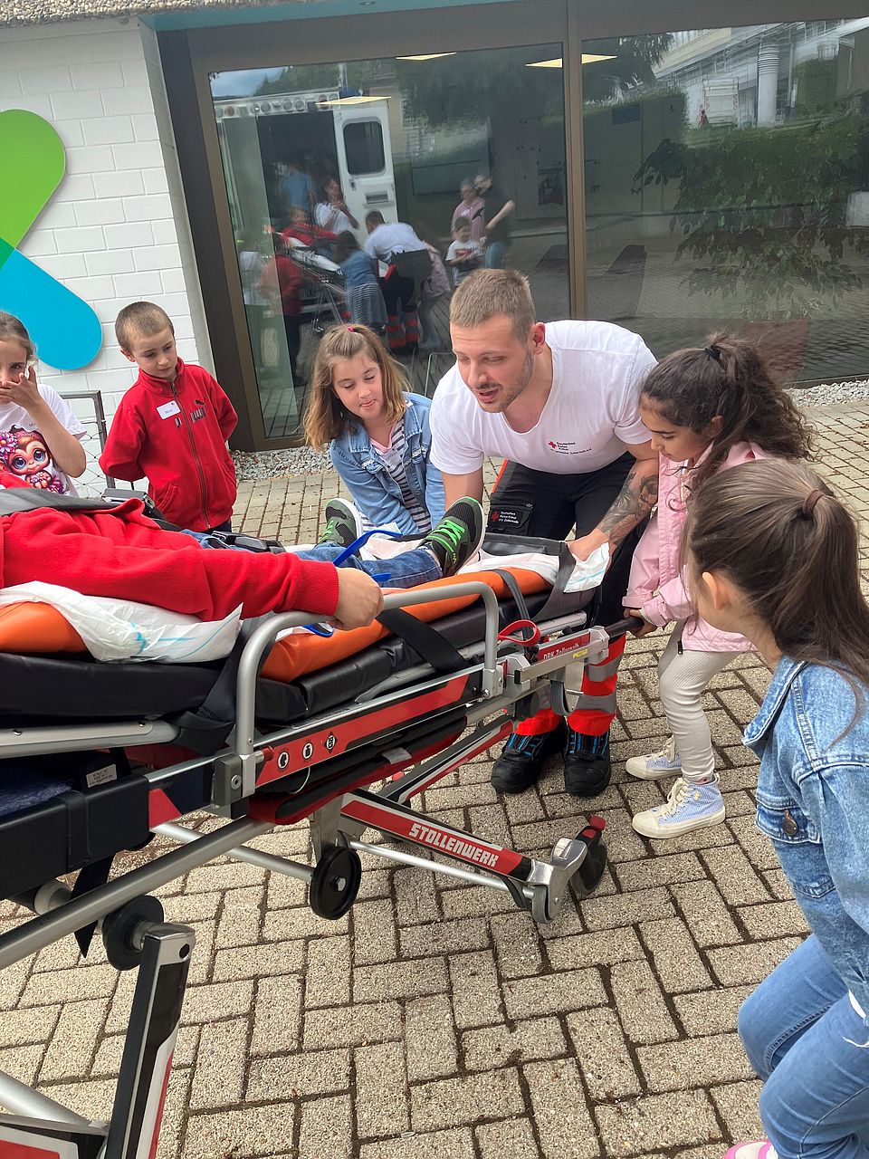 Kinder helfen bei Übung, die Bahre in den Krankentransportwagen zu schieben
