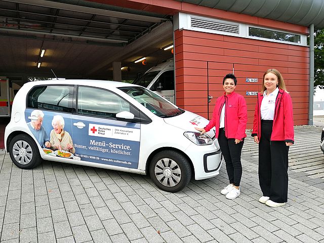 DRK Mitarbeiter / Menü-Service stehen vor DRK Fahrzeug